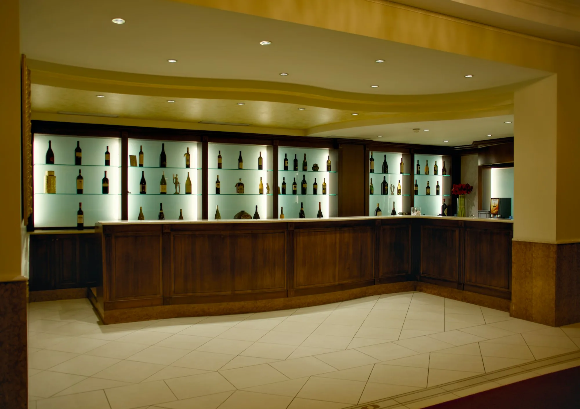 Wooden bar with bottles arranged in illuminated display cabinets