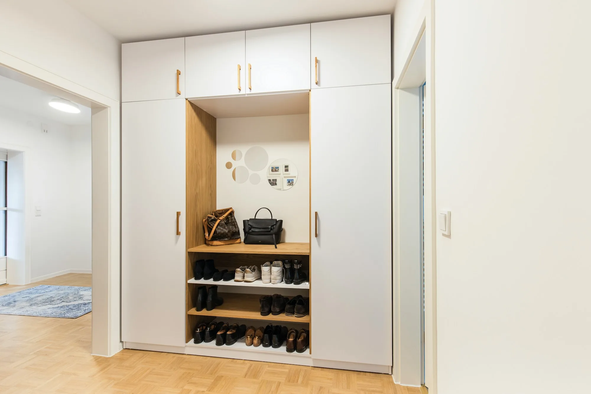 White fitted storage unit with shoe shelves and a handbag display