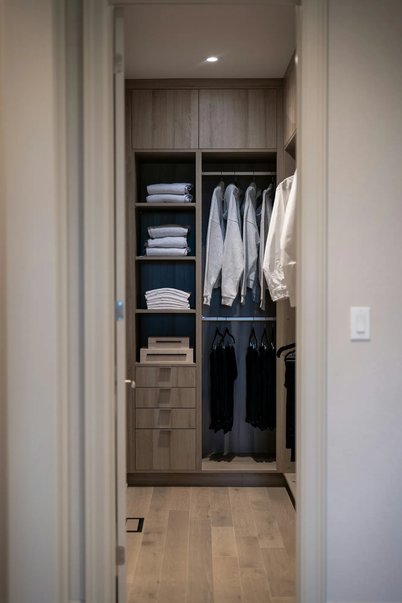 Organized walk-in closet with hanging clothes, drawers and open shelves