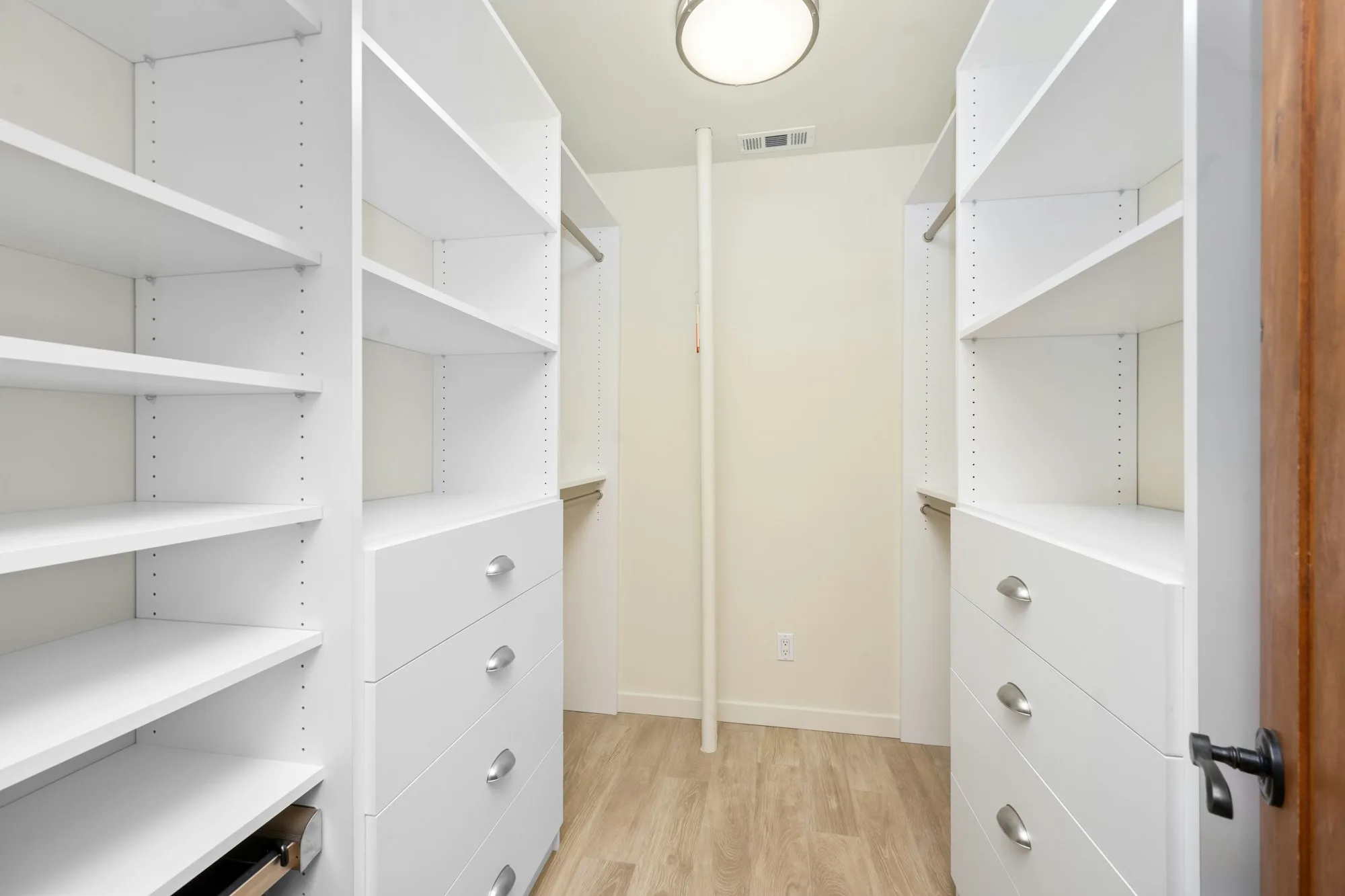 Walk-in closet with white built-in shelves, drawers and hanging storage