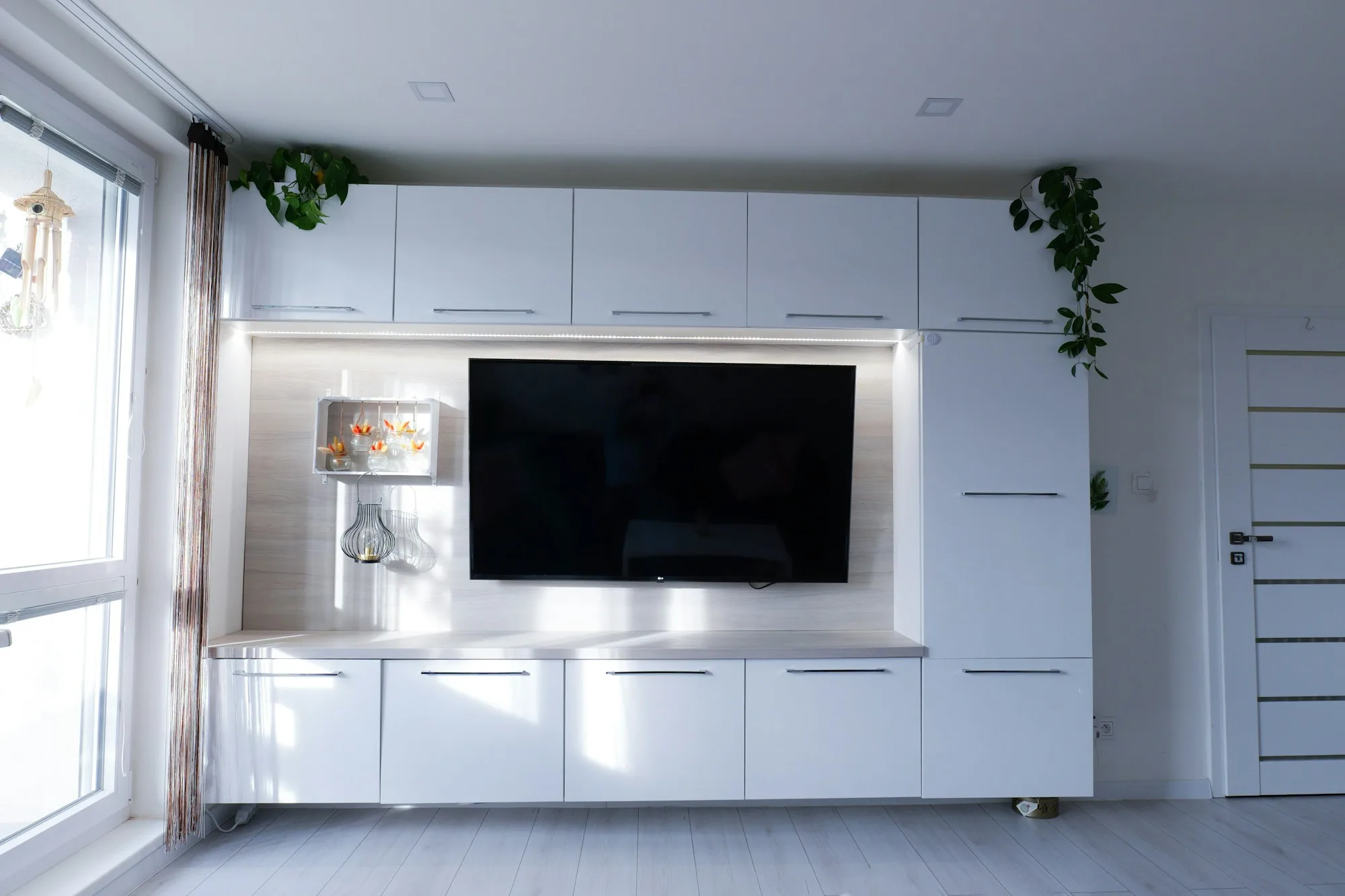 White entertainment center with a large television in a minimal living room