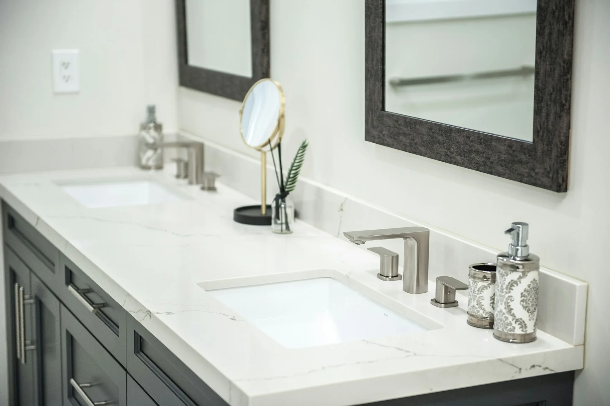 Double bathroom vanity with quartz counters, paired sinks and framed mirrors