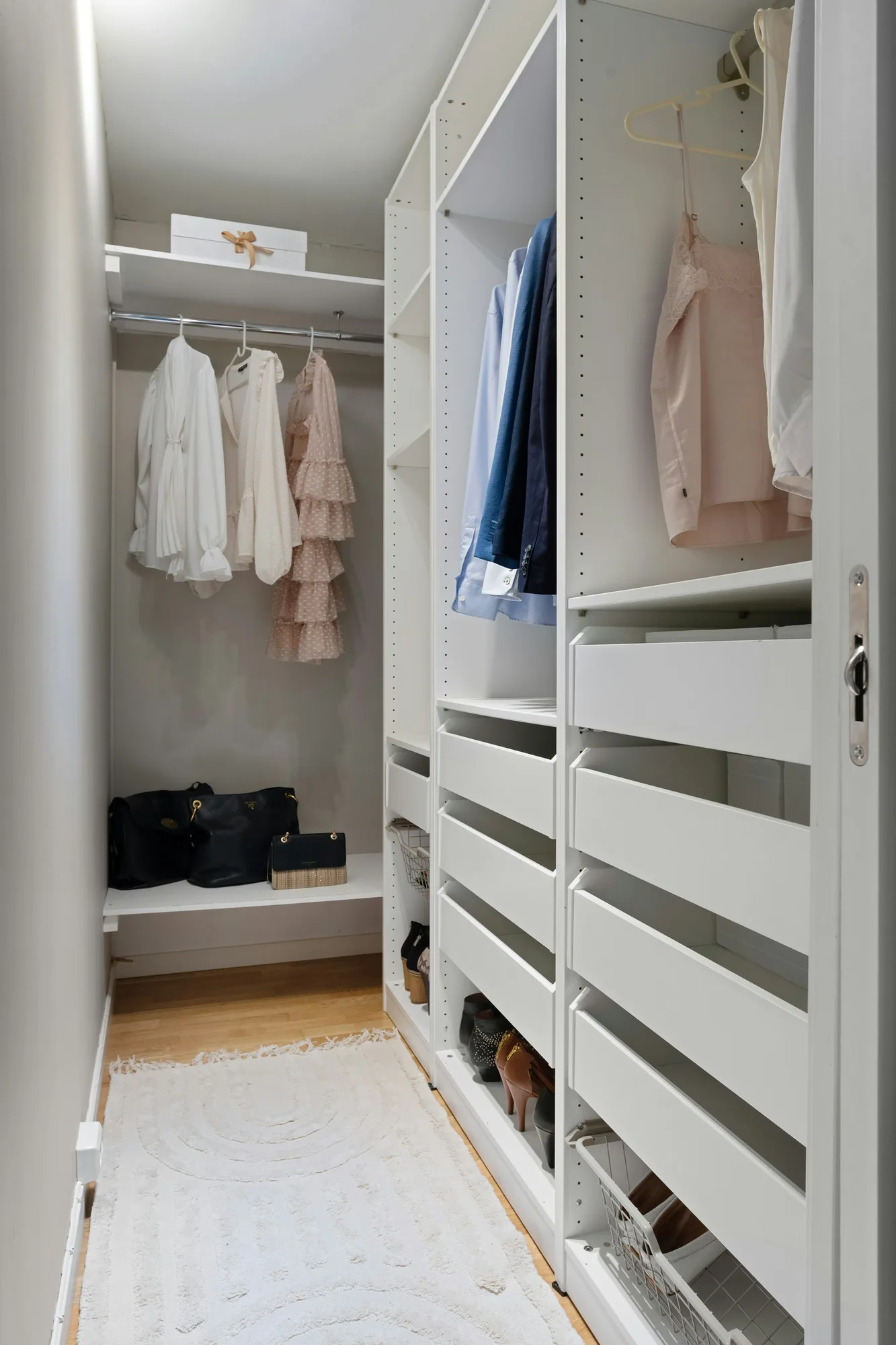 Walk-in closet with white fitted shelving, drawers and hanging rails