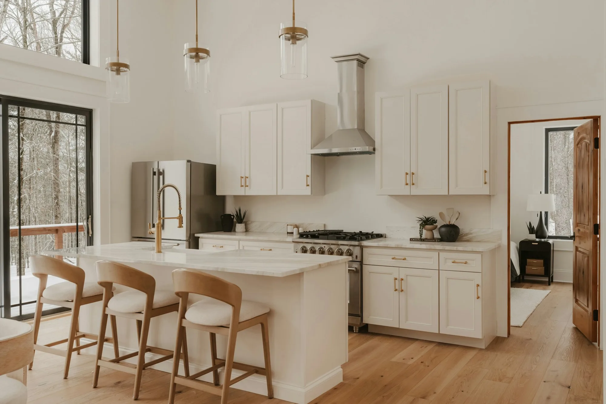 Bright white kitchen with a generous island, bar stools and garden views